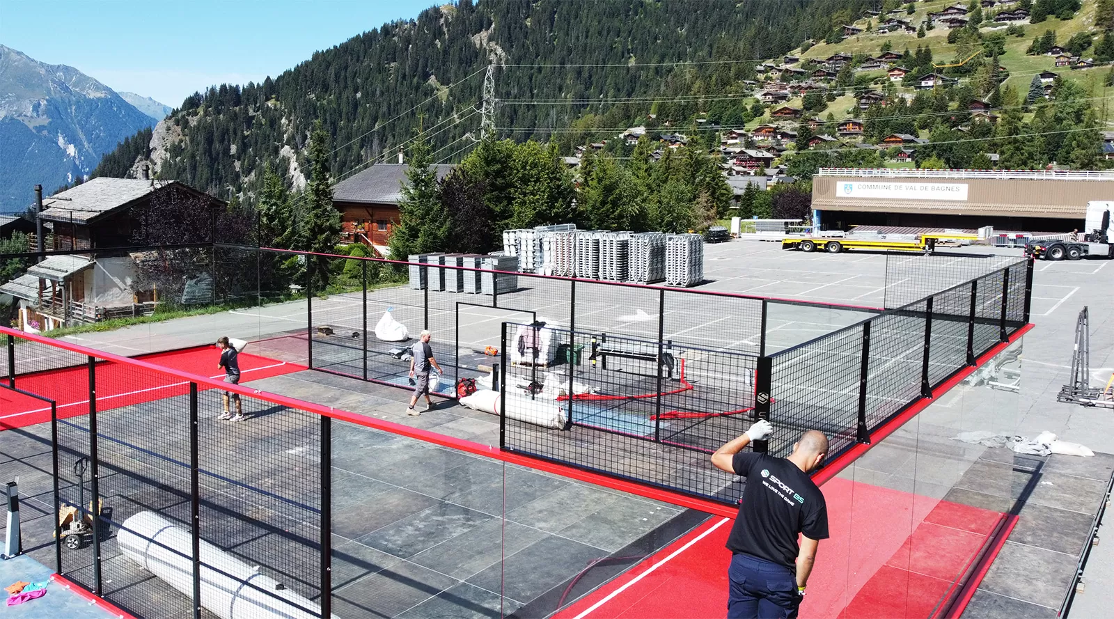SportBS team installing a red padel court in a mountain valley setting