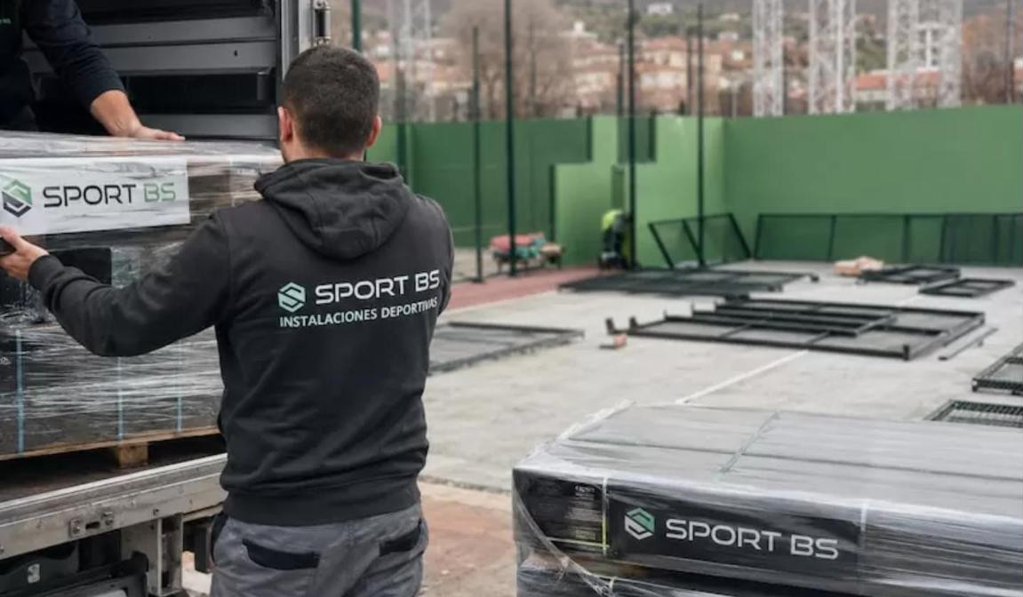 Padel court installation in the UK: SportBS fitter unloading steel structures and glass panels from the delivery lorry