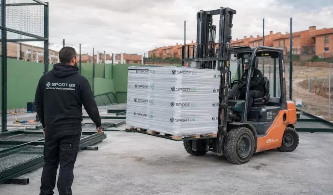 Padel court installer in the UK: SportBS team unloading glass panels with a forklift before installation